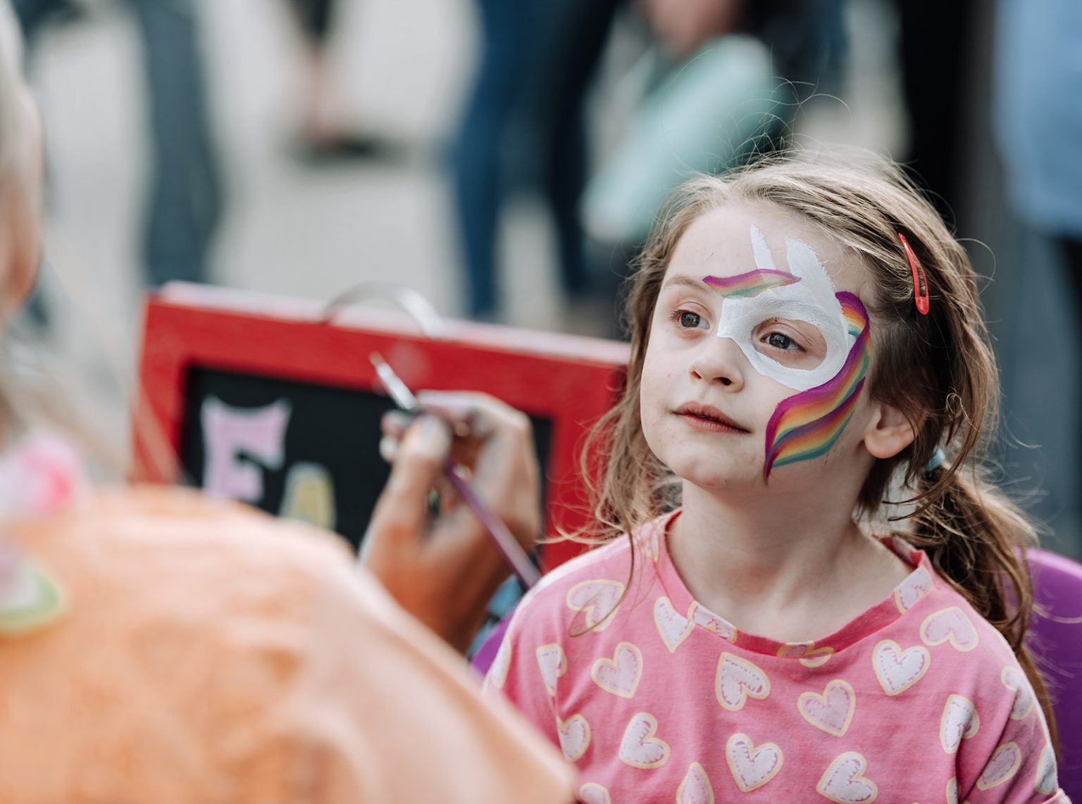 A small child with face paint from Buskerfest 2025
